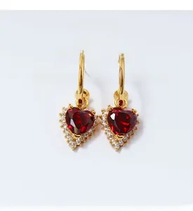 Macro shot of elegant red heart zircon earrings with gold plating and cubic zirconia detail
