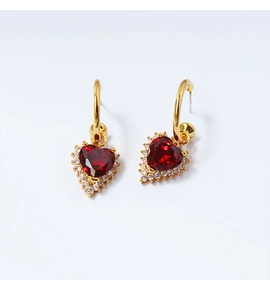 Detail of vintage heart-shaped red ruby drop earrings with white zircon accents and gold plating