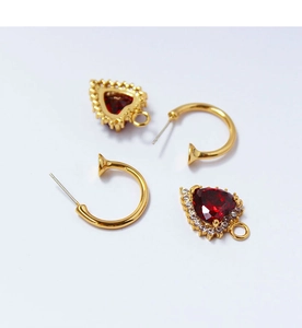 Detail view of gold C-shaped hooks and ruby heart pendants with zircon pave edges