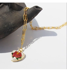 Detail of vintage gold paperclip chain and heart enamel pendant with red rose and green leaves