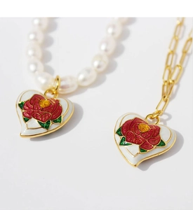Detailed macro view of vintage heart necklaces with enamel roses and pearl chain detailing