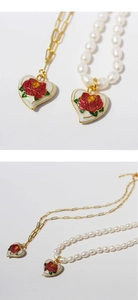Detail of vintage heart pendant with red rose relief on gold and pearl necklaces