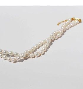 Detail of double-layer pearl necklace with golden clasp and adjustable chain extender