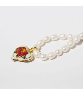 Detail of white irregular pearls and gold heart pendant with red enamel rose