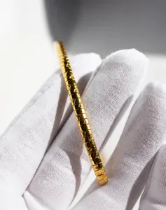Gros plan d'un collier chaîne serpent dorée avec texture de maille et motifs gravés