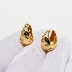 Gold plated huggie earrings with star engravings and zircon stones in minimalist style