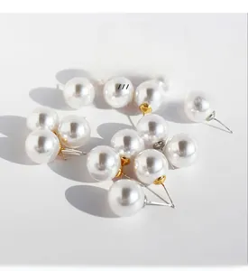 Detail of round pearl earrings with gold-plated brass and zircon accents on white background