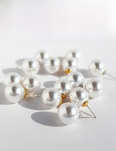 Macro shot of large round white pearl earrings with gold and silver needle studs