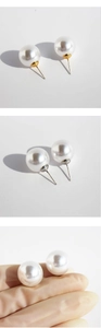 Macro view of large white round pearl earrings with gold and silver base detail