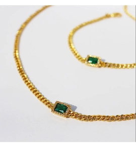 Detail view of gold-plated necklace and bracelet set with rectangular emerald zircon stones