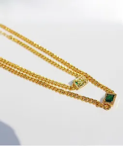 Macro shot of gold-plated curb chain with rectangular emerald zircon pendants and crystals