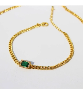 Detailed macro view of emerald-green zircon centerpiece on gold-plated Cuban chain link
