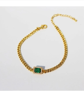 Detail of gold Cuban chain bracelet with emerald-cut green zircon and lobster clasp