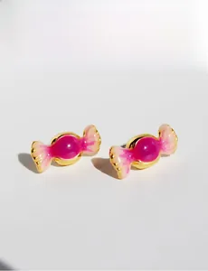 Gros plan sur des boucles d'oreilles en forme de bonbon en métal doré et émail rose