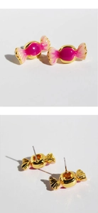 Détails macro de boucles d'oreilles en émail rose en forme de bonbon avec dorure et tige