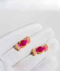 Détail de boucles d'oreilles bonbon en émail rose fuchsia et placage doré chic