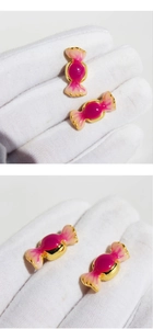 Gros plan sur des boucles d'oreilles bonbon en émail rose foncé et bordures dorées fines