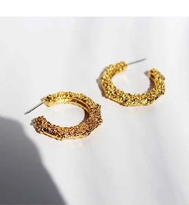Detailed view of gold-tone C-shape hoop earrings with vintage hammered lava texture