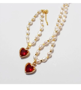 Dettaglio collana e bracciale di perle d'acqua dolce con pendenti a cuore in rubino rosso