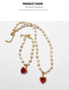 Dettaglio della collana di perle barocche con gemma a cuore rosso e oro