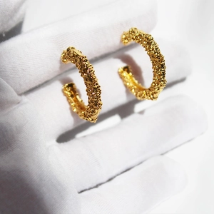 Textured gold-plated C-shaped hoop earrings with irregular hammered lava pattern