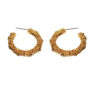 Golden C-shaped hoop earrings with irregular hammered texture on a white background