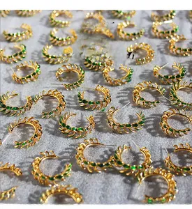 Detailed view of vintage gold-plated leaf hoop earrings with green zircon pavé stones