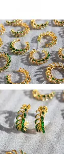 Detail shot of vintage golden C-shape earrings with green leaf enamel under natural light