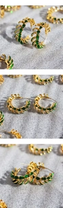 Macro detail of vintage green leaf enamel and gold layered hoop earrings on grey texture