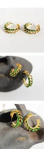 Detail shot of vintage green leaf hoop earrings with textured gold metal and enamel work
