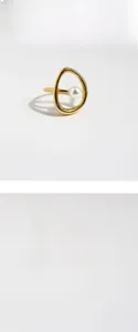 Détail de bague dorée abstraite ajourée avec une perle blanche ronde élégante
