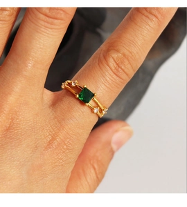 Dettaglio di un anello vintage con zircone smeraldo dorato indossato con doppia fascia