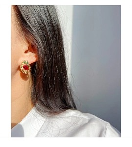 Detail of vintage French brass earring with a large red teardrop stone and green accents