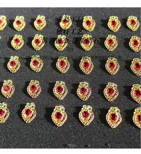 Detail of strawberry-shaped gold-plated brass earrings with red and green cubic zirconia