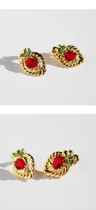 Detailed macro view of vintage strawberry stud earrings with red and green zircons
