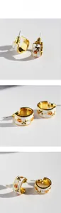 Detail of gold-plated tulip enamel earrings with vintage floral patterns and C-shaped design