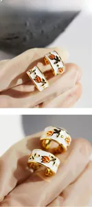 Detailed macro view of gold-plated C-shaped earrings with white enamel tulip pattern