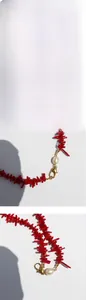Macro detail of red coral branch necklace with white pearl and gold heart clasp