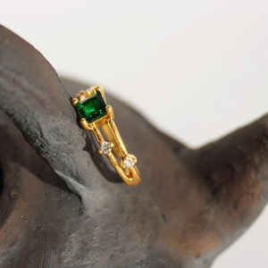 Anello retrò dorato con zircone verde taglio smeraldo e finitura opaca su sfondo scuro