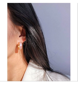 Detailed view of pink zircon C-shaped hoop earrings with gold base on model