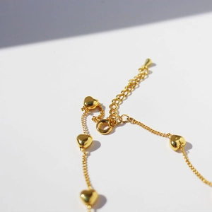 Elegant gold-tone layered necklace with heart-shaped pendants and adjustable chain