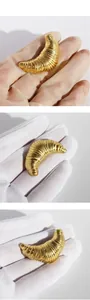 Macro detail of gold plated croissant brooch showing refined texture and 3D metal carving