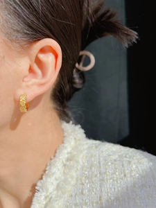 Detail of vintage gold flower relief earrings worn on model with elegant texture