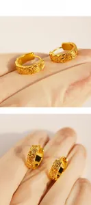 Macro detail of vintage gold hoop earrings with embossed flower and leaf patterns