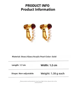 Detail view of gold vintage U-shaped clip-on earrings with red glass and white pearls