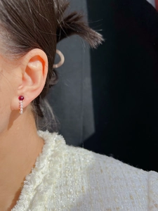 Detailed close-up of vintage red glass earrings with pearl accents on a model