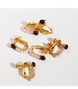 Detail of vintage U-shaped gold-plated brass ear clips with red zircon and pearls