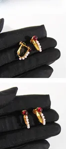 Detail view of vintage red glass U-shaped earrings with white pearls and gold clips