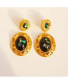 Detail of vintage oval gold-plated earrings with black stone inlay and colorful zircon