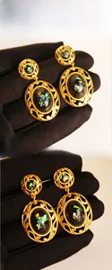 Close-up of vintage gold hollow filigree earrings with black opal-style stone inlay